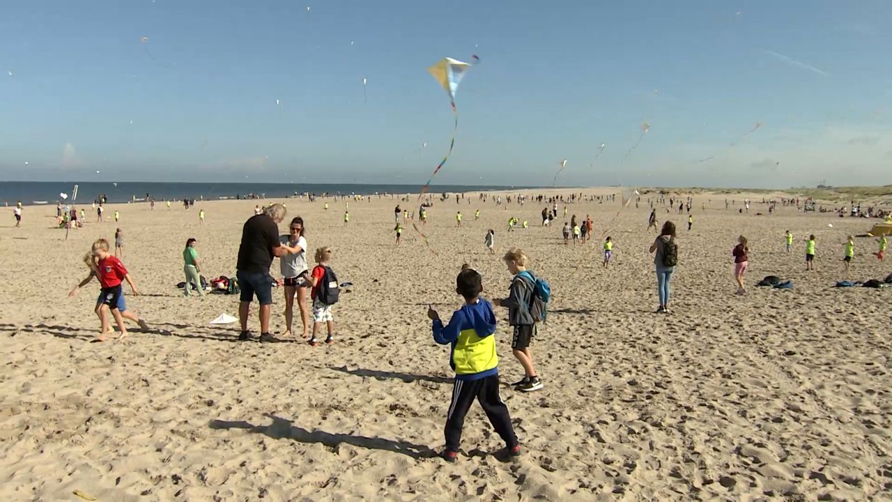 Honderden kinderen vliegeren op strand in Monster